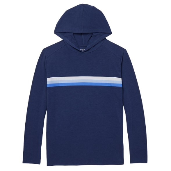 A man wearing a blue Horizon UPF 50+ Performance Hoodie, standing on a sunny beach with waves in the background, showcasing the fabric's lightweight feel.