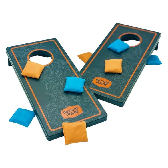 Adventure Compact Cornhole Set displayed on a picnic table during a family gathering.