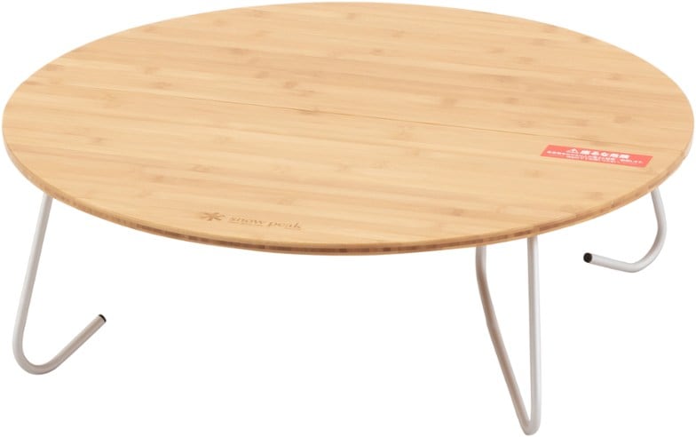 Snow Peak round Japanese-style camping table set up in a forest picnic scene