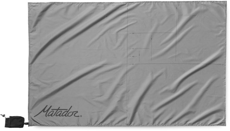Mini waterproof pocket blanket unfolded on a grassy field, perfect for picnics.