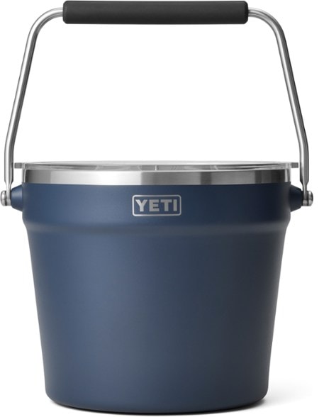 A YETI Rambler Roadie 20 stainless steel cooler bucket brimming with ice and assorted cold beverages, set against a vibrant outdoor picnic backdrop.