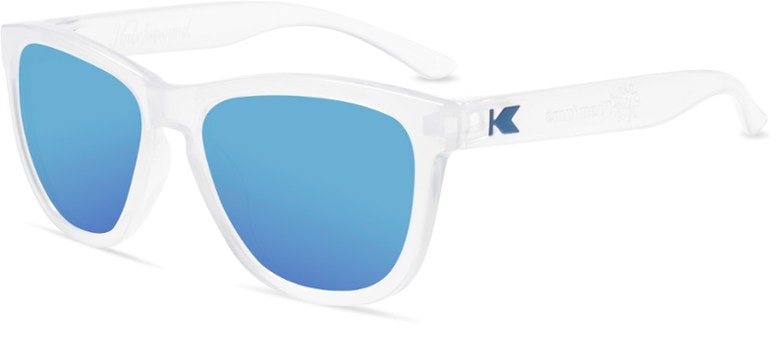 A child wearing blue KiddieGuard UV400 polarized sunglasses, smiling brightly while playing outdoors on a sunny day.