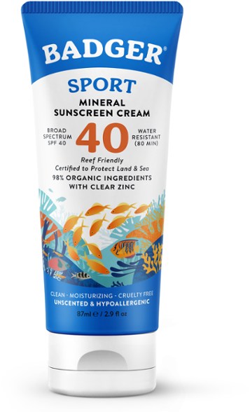 Front view of ActiveShield mineral sunscreen tube standing on a beach towel next to sunglasses