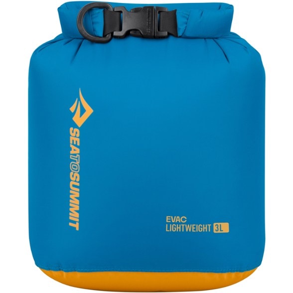 AquaShield Ultra-Light Dry Bag in use, showing a person compressing air out by sitting on it, ideal for saving space in a backpack.