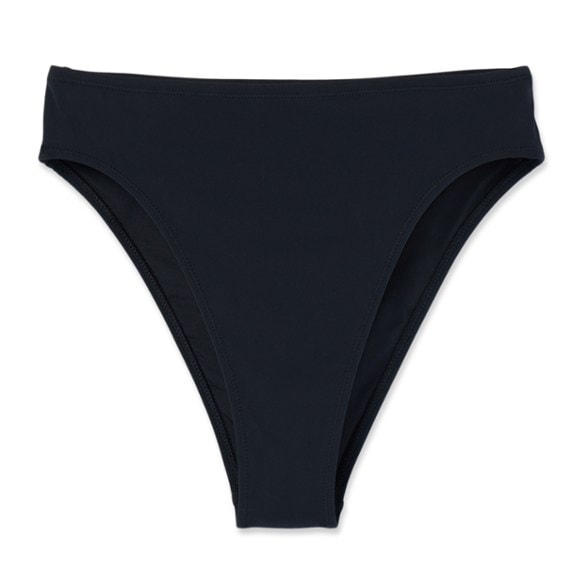 Model smiling on a sunny beach, wearing Serene Shore high-waisted bikini bottoms in a vibrant blue.