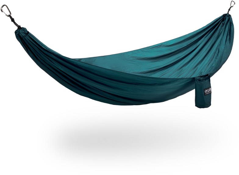 EmberLight Go portable hammock in vibrant blue, fully set up between two trees in a lush green forest, showcasing its comfortable and spacious design perfect for a camping hammock.