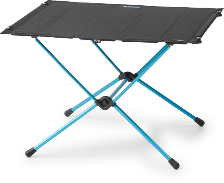 TrailMate Pro portable camping table set up beside a campfire at dusk