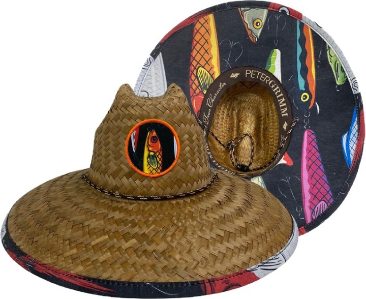 Front view of a straw lifeguard hat featuring a wide brim and a detailed fishing lure pattern on the underbrim, set against a sunny beach background.
