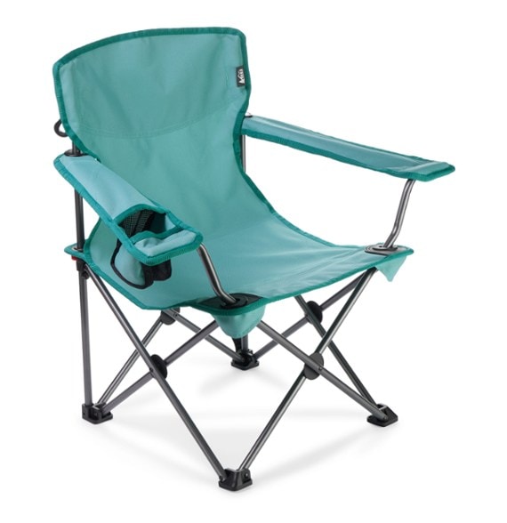 Little boy sitting in a kids camp chair by the campfire
