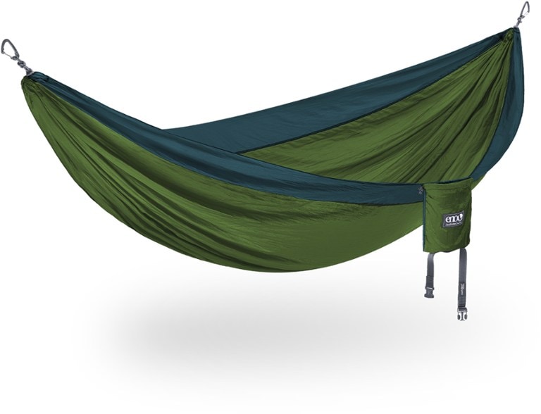 A vibrant red ENO DoubleNest hammock strung between two trees in a lush green forest, showcasing its generous size for two people.