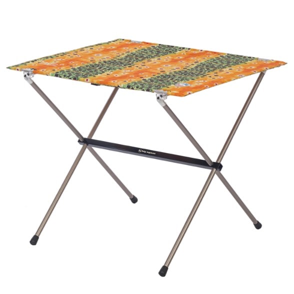 A person easily setting up a Trailblazer folding camp table in a sunny forest clearing, demonstrating its simple assembly.