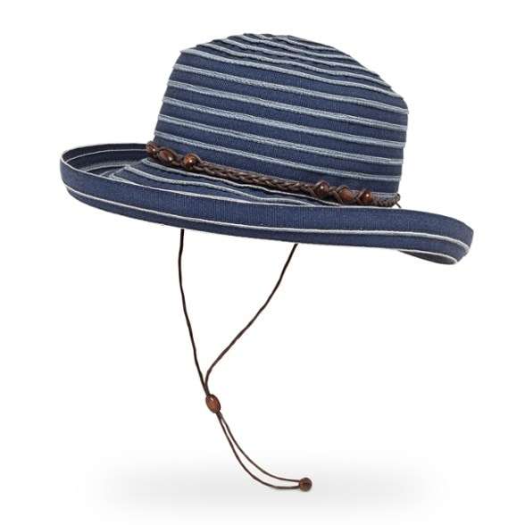 A woman smiling outdoors, wearing The Traveler's Escape Packable Sun Hat in a natural light color, showcasing its wide brim and elegant beaded band.