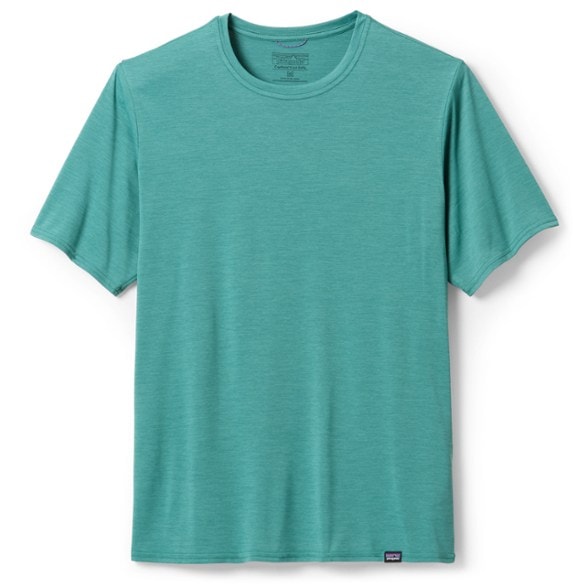 Front view of a man wearing the Patagonia Capilene Cool Daily men's running shirt in a vibrant blue color, mid-stride on a scenic trail.