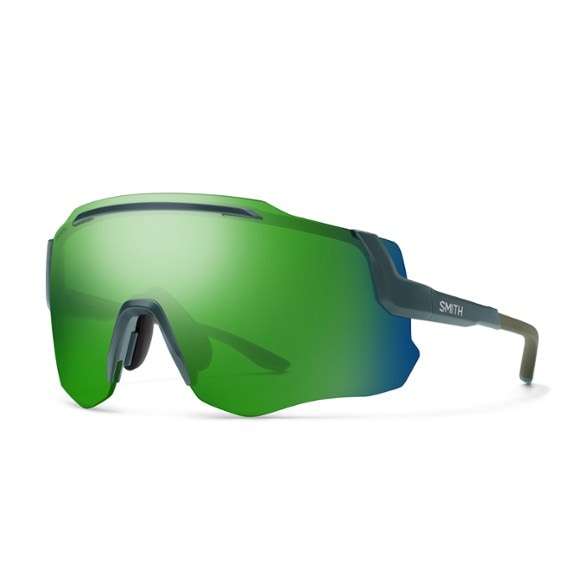 Cyclist wearing Momentum ChromaPop Elite cycling sunglasses with green tint on a sunny road, showcasing the wraparound fit and clear vision.