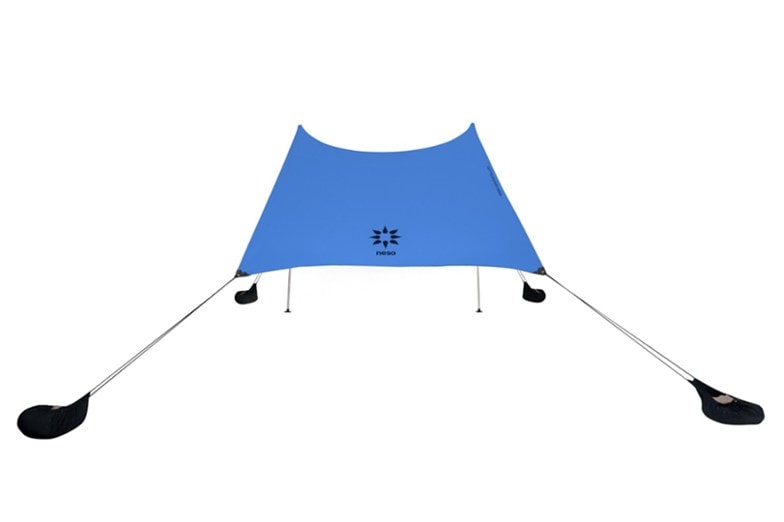 AuraShade Pro portable sunshade set up on a sandy beach, showcasing its stretched canopy and natural sand anchors.